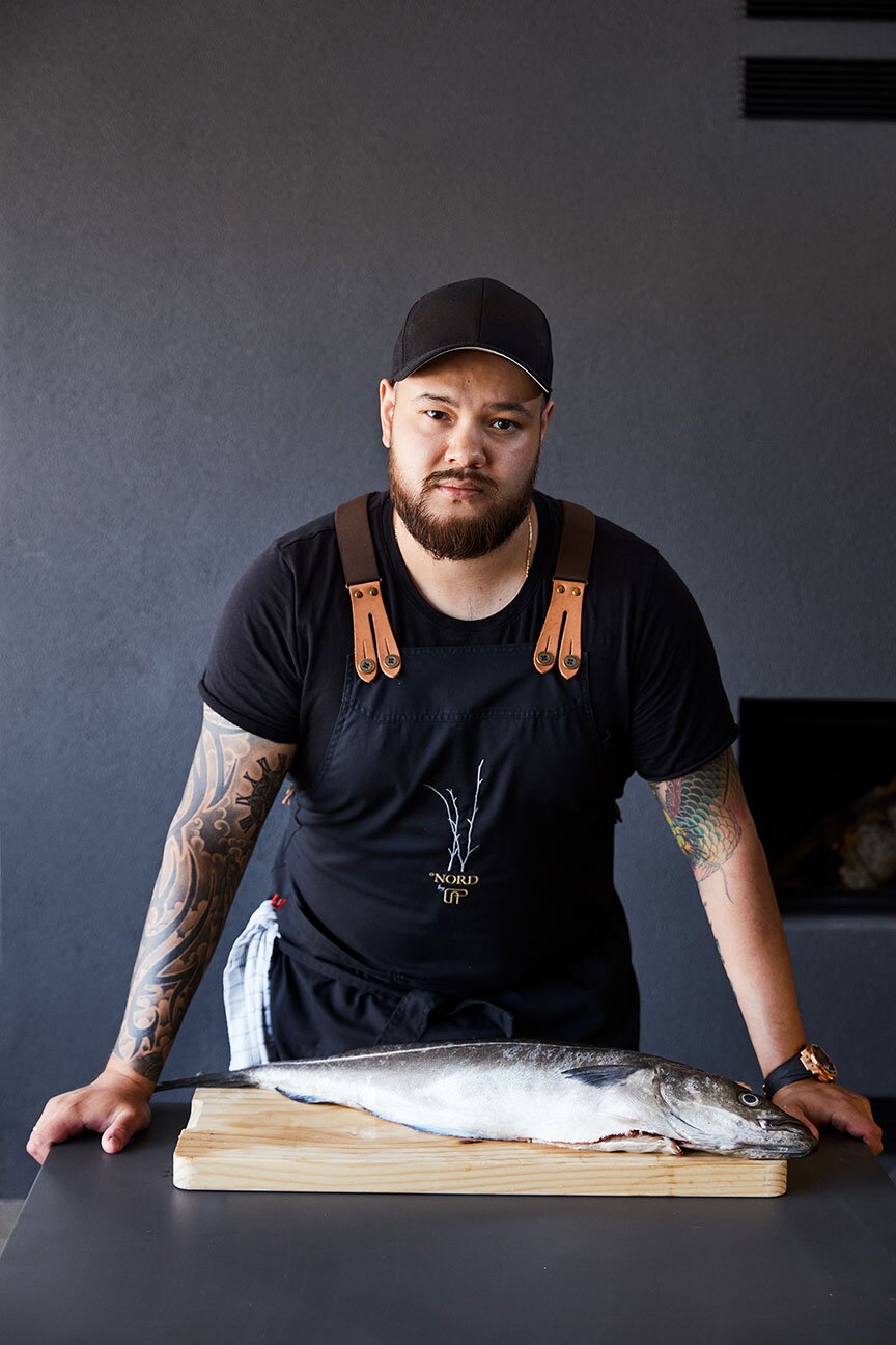 Christian André Pettersen, chef cuisinier primé, se tient devant un lieu noir de Norvège frais posé sur une planche à découper.