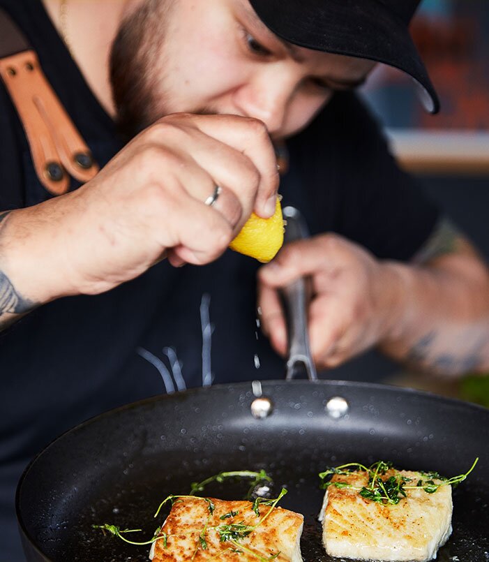 le chef fait cuire le lieu noir à la poêle